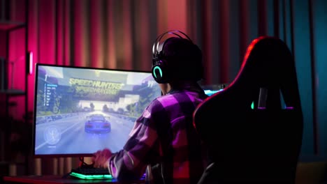 un adolescente asiático emocionado celebra la victoria y baila mientras juega a un videojuego en la computadora, jugando a un juego de carreras