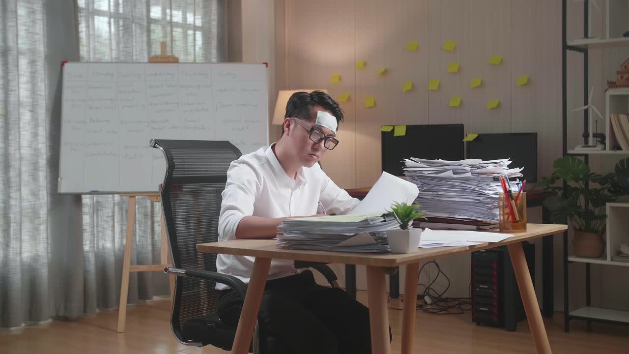 hombre asiático enfermo trabajando duro con documentos en la oficina
