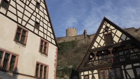 sunlight hitting beautiful half timbered architectural houses, in the background the scenic castle overviewing kaysersberg