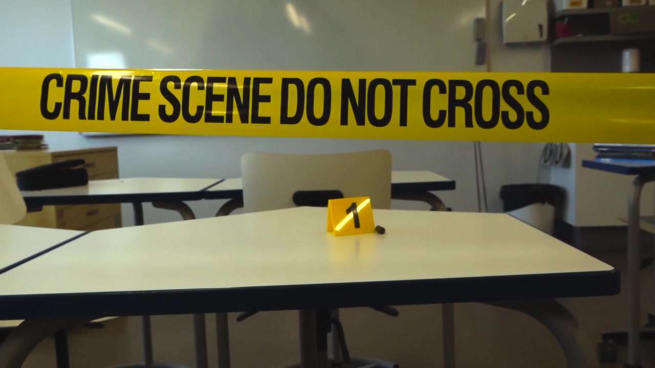 Aula vuota transennata con nastro della polizia dopo un incidente di sparatoria scolastica, con un bossolo e un segnaposto per prove su un banco di uno studente per scopi di indagine forense