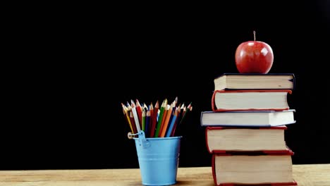 apple on book stack with color pencil on table