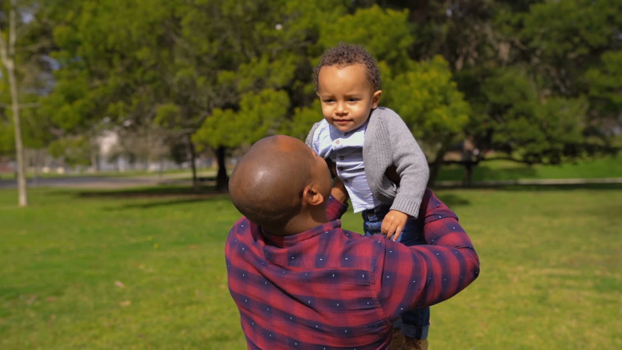 padre sosteniendo a un niño de raza mixta en los brazos, girándolo alrededor