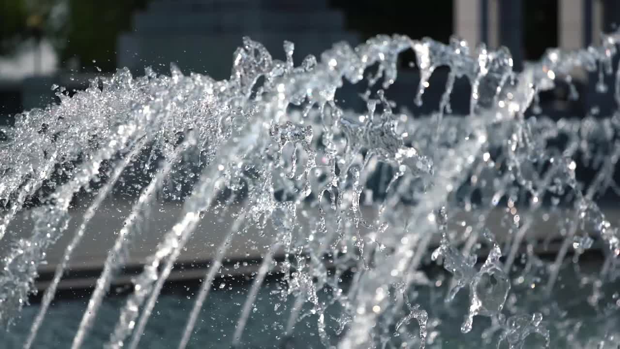 Fountain expelling transparent water outdoors in slow motion during hot sunny day