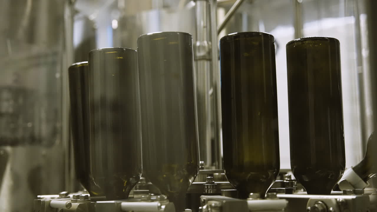 Empty wine bottles being washed upside down on factory assembly line