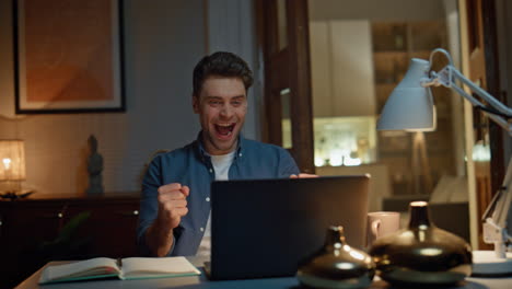 focused man staring computer reading email at dark flat closeup. excited winner