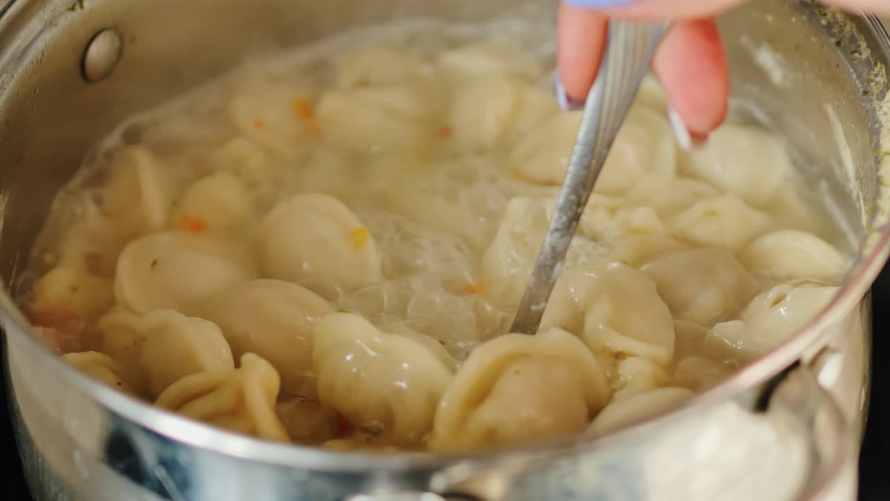 Un cucchiaio mescola delicatamente dei morbidi gnocchetti che affiorano in una base di zuppa calda e spumosa