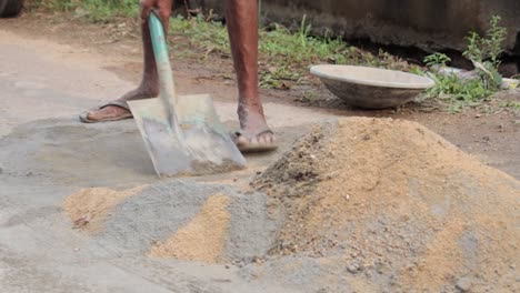 crear una mezcla de hormigón en las calles, un trabajador masculino mezclando arena y cemento usando una pala para un pequeño proyecto de construcción