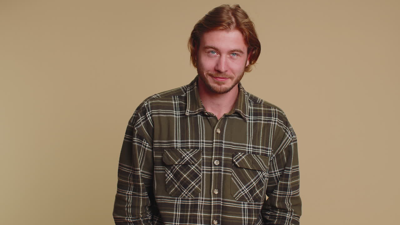 미소 짓는 장난스러운 행복한 남자가 눈을  ⁇ 이고, 이빨이 있는 미소로 카메라를 쳐다보고, 눈을  ⁇ 고 유혹합니다.