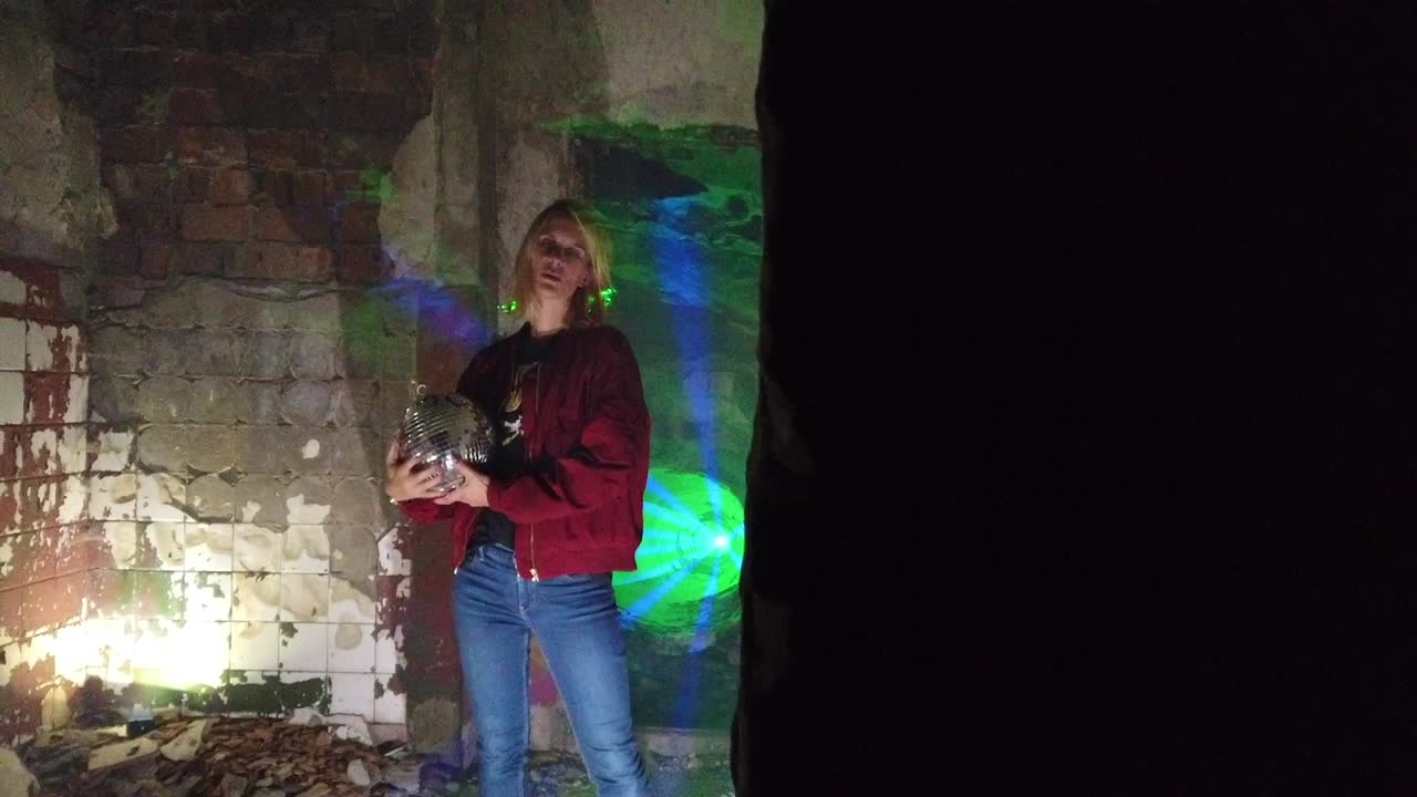 Spectacular slow motion cinematic shot of a berlin bad girl DJ with a mirror disco ball in old damaged house party club location. Foto video shoot on lost places in nature 1080, 24p by Philipp Marnitz