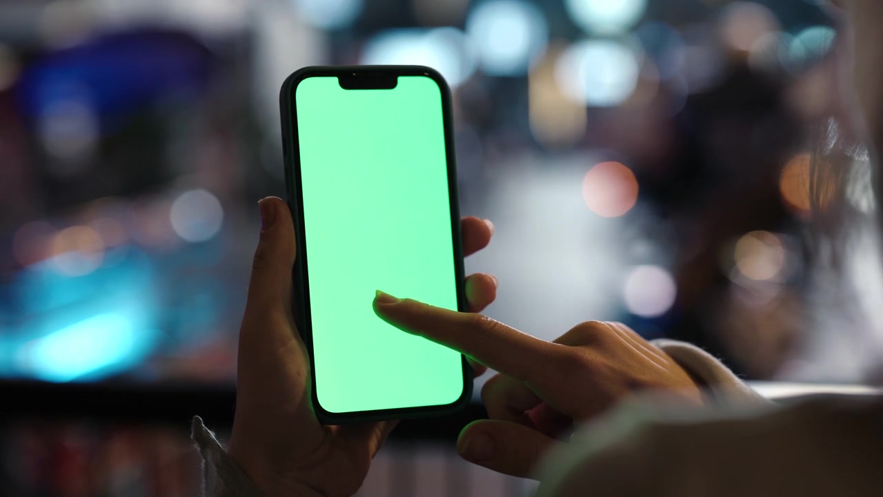 Persona che tiene uno smartphone con schermo verde e tocca lo schermo