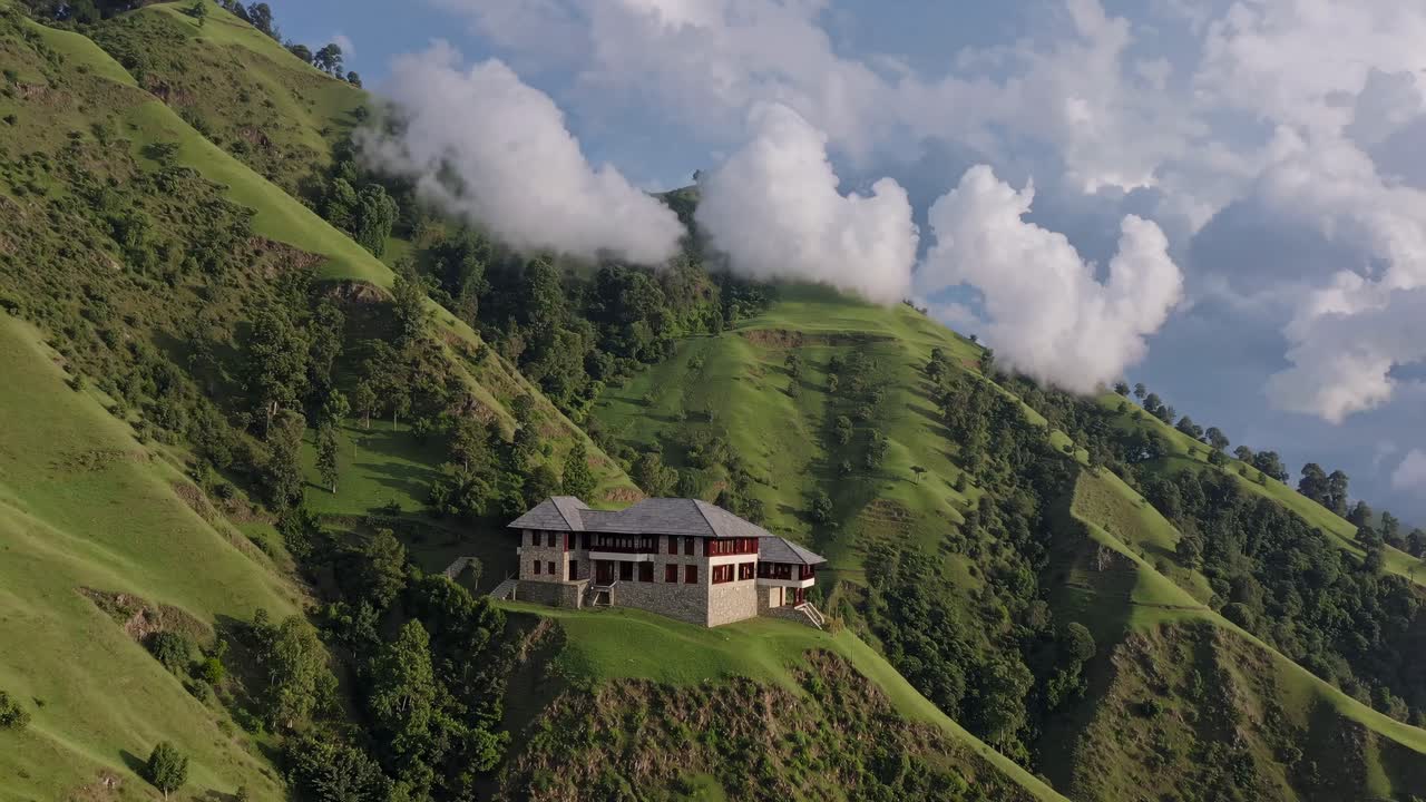 Luxurious mountain lodge nestled on a lush hillside, surrounded by rolling green slopes and a breathtaking valley, under a dramatic cloudy sky
