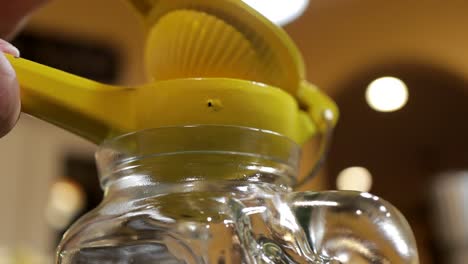 Squeezing-lemons-with-squeezer-hand-press-into-jar