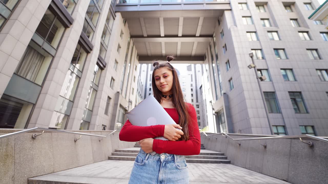 Giovane donna con laptop sulle scale della città