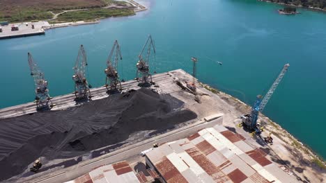 heap of iron ore coal with harbour cranes at ploce harbour in croatia