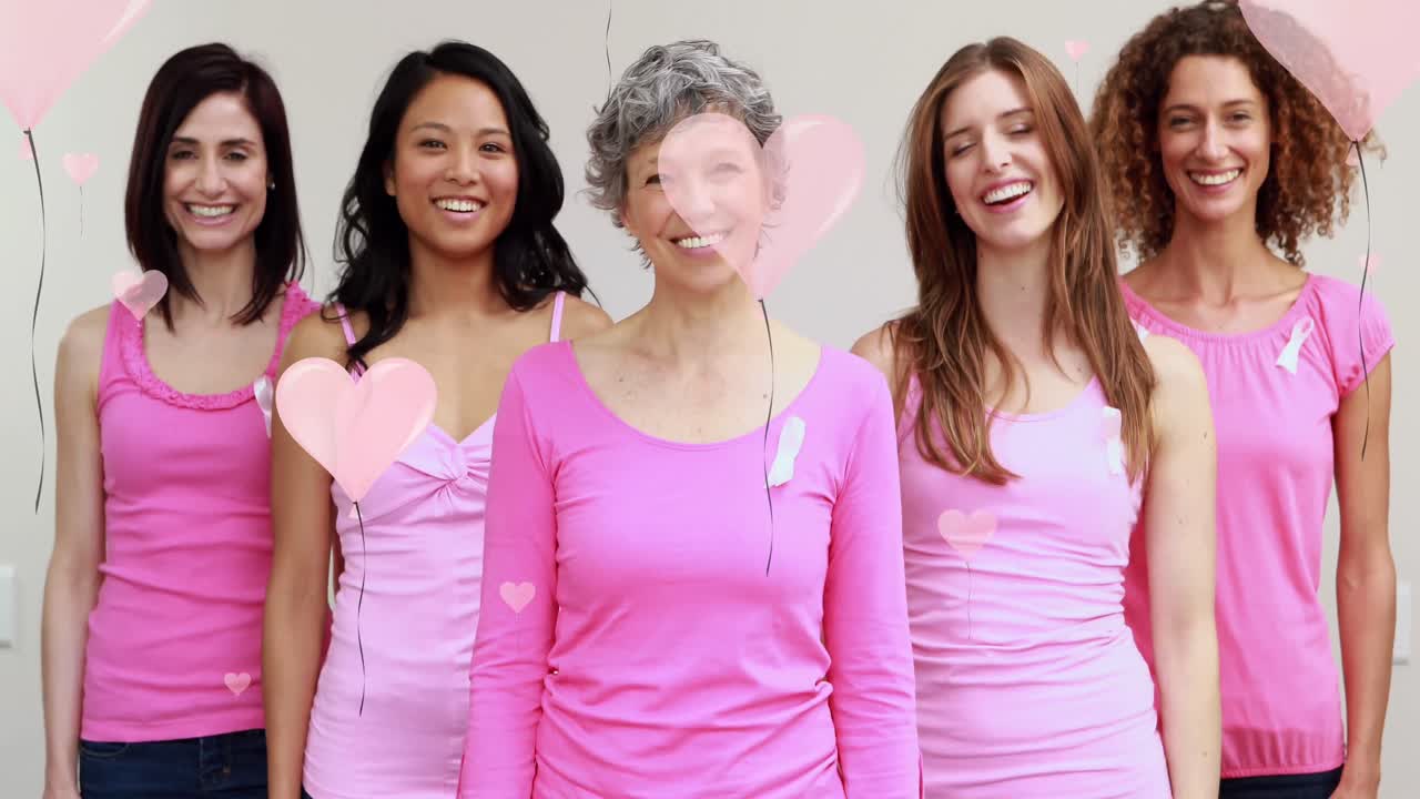 Animación de corazones rosas flotando sobre un grupo diverso de mujeres sonrientes vestidas de rosa con lazos contra el cáncer