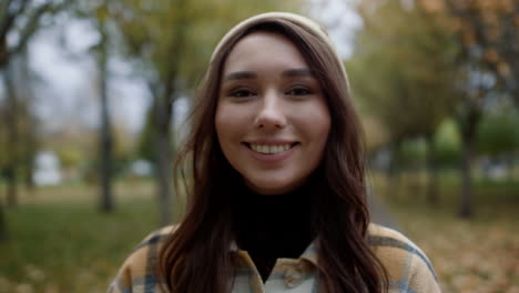 Portrait-of-smiling-girl-standing-in-park.-Close-up-view-of-beautiful-miss.