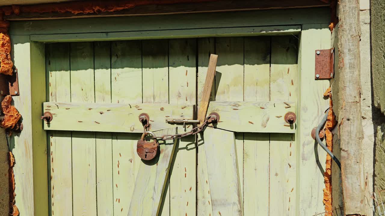 Heavy chain, rusted lock secure aged wooden doors in abandoned Soviet structure