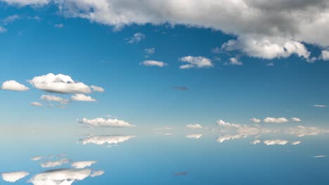 futuristic background consisting of time lapse clip of white fluffy clouds over blue sky and their reflection, video loop