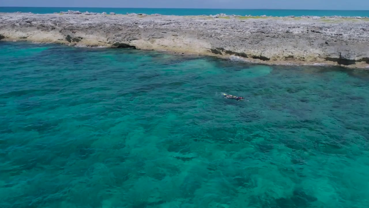 Vista aerea con drone di un'isola deserta delle Bahamas con barca a vela solitaria e snorkelisti