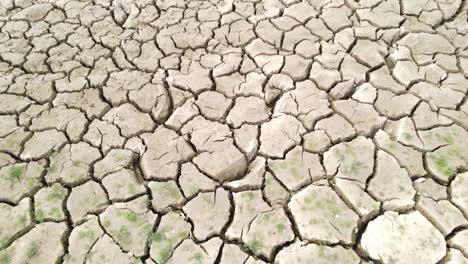 Dry-cracked-drought-fractured-land-aerial-view-descent-over-hot-barren-environment