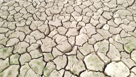 dry cracked drought fractured land aerial view descent over hot barren environment