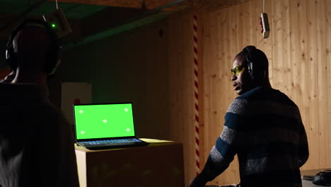 green screen laptop in shooting range next to man successfully shooting targets