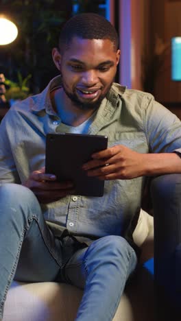 vertical video black remote worker navigating on tablet next to screen running analytics