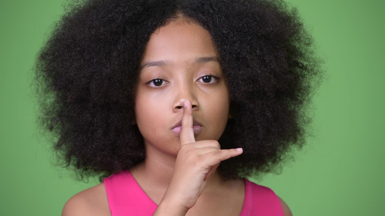 Young cute African girl with finger on lips