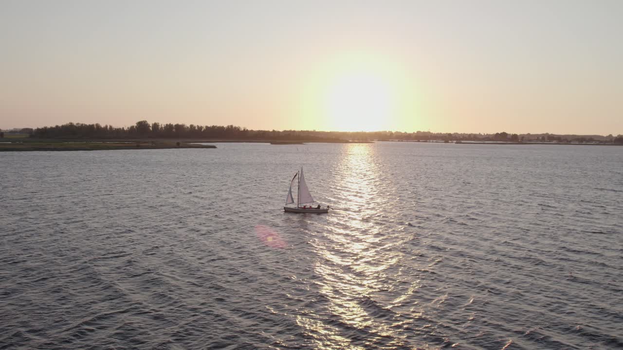fotografía lateral de un yate de vela con los lugareños en el lago fluessen friesland con luz mágica, aérea