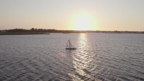 Seitliche-Schwenkaufnahme-Einer-Segelyacht-Mit-Einheimischen-Auf-Dem-See-Flüßen-In-Friesland-Mit-Magischem-Licht,-Luftaufnahme