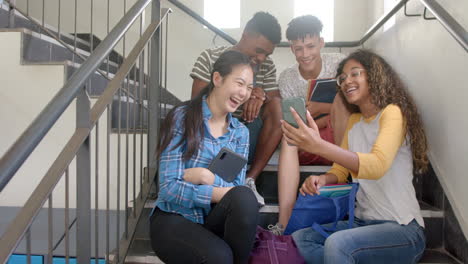 Diverse teenagers share a laugh on high school stairs