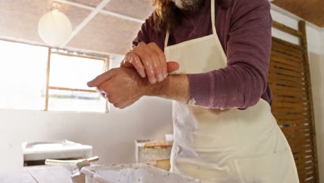 Male-potter-washing-hands-after-working-on-pottery-wheel