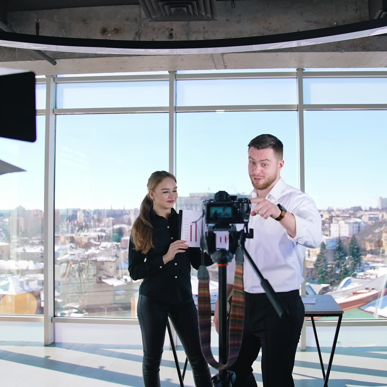 Young business people recording video. Handsome guy talking on camera inviting to join the project. Creative bloggers man and woman speaking on professional camera in studio