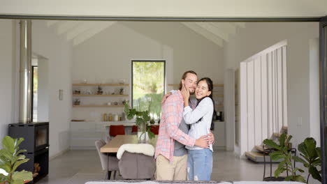 a biracial couple hugs warmly in a modern home