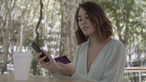 mujer latina haciendo el pago con tarjeta de plástico a través de un teléfono inteligente