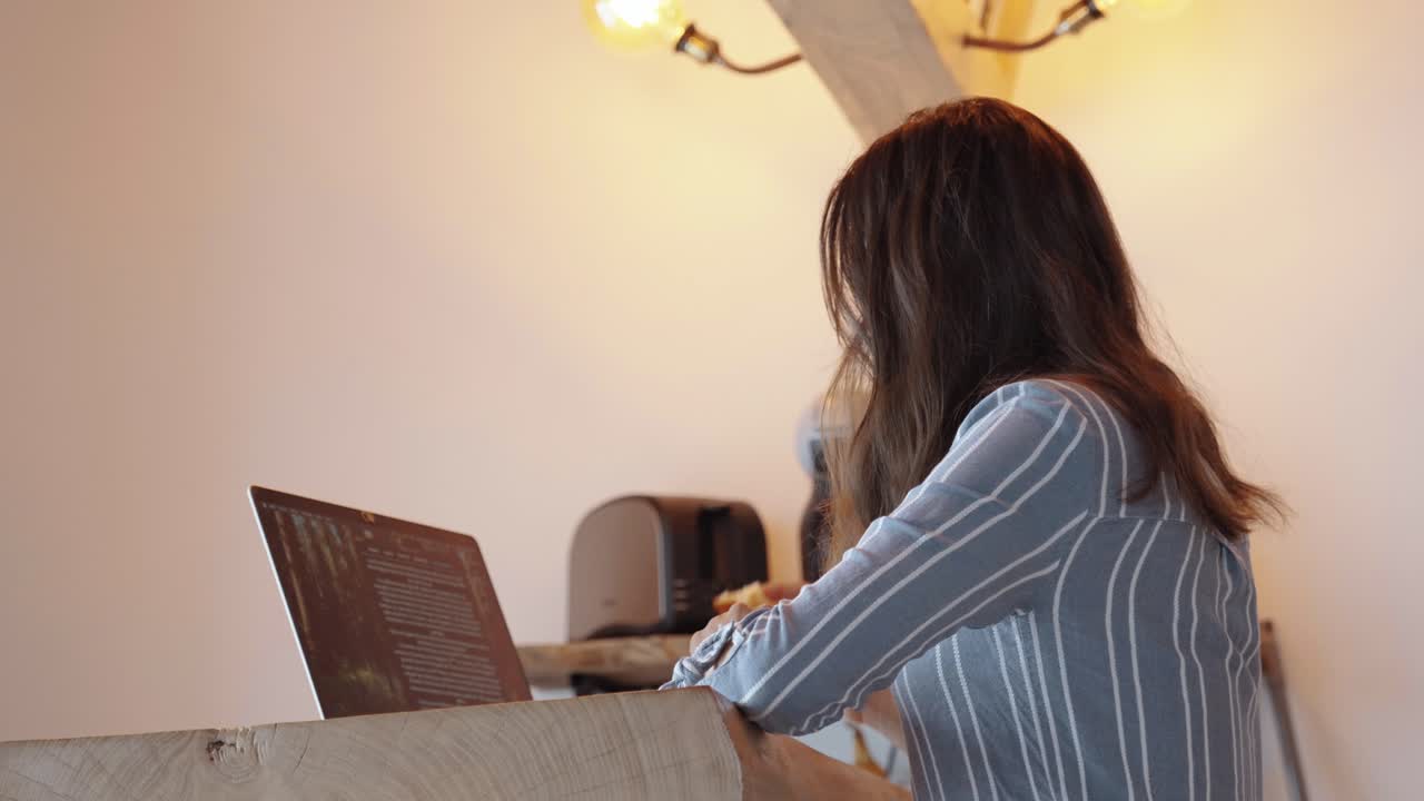 Woman focused on laptop in cozy workspace, warm beige tones, symbol of productivity and modern remote work lifestyle