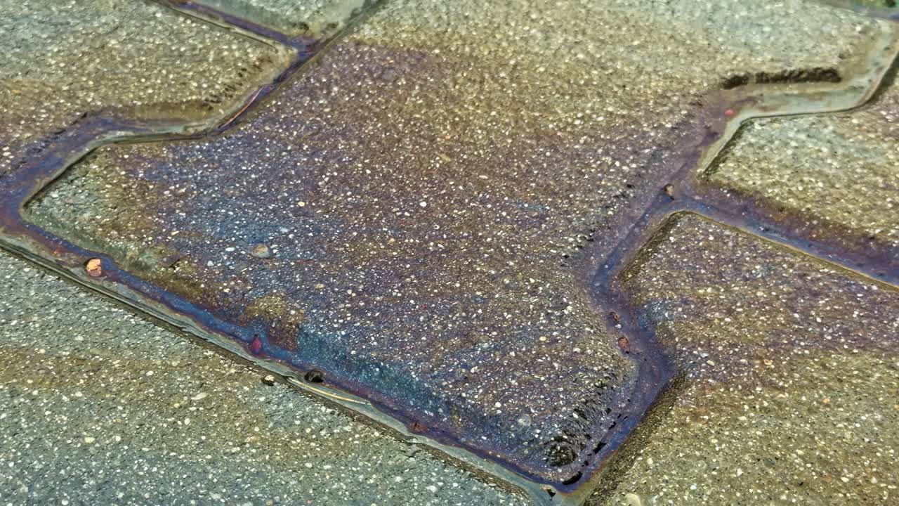 Iridescent rainbow-like pattern on a wet textured pavement surface oil gasoline spill