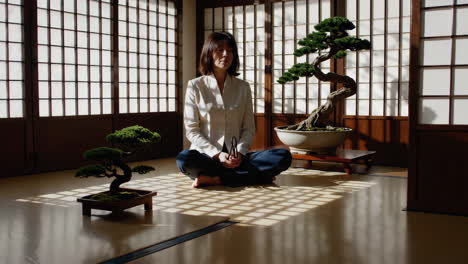 woman meditating with bonsai trees in a japanese-style room
