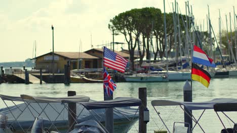 Group-of-flags-on-boats-blowing-in-the-wind-while-moored-in-a-peer-of-a-small-port