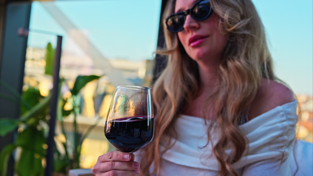 Close up of a woman swirling a glass of red wine at a terrace