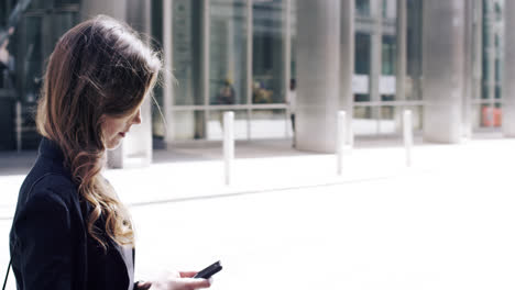 atractiva mujer de negocios viajera que usa un teléfono inteligente en la ciudad de londres