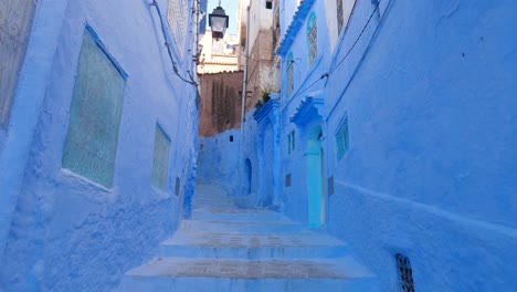 Vista-De-Inclinación-Lenta-Hacia-Abajo-A-Lo-Largo-De-La-Icónica-Calle-Vacía-Pintada-De-Azul-En-Chefchaouen