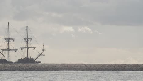 16th century galleon andalucia replica ship arriving at port in a beautiful cloudy day at sunrise behind a breakwater