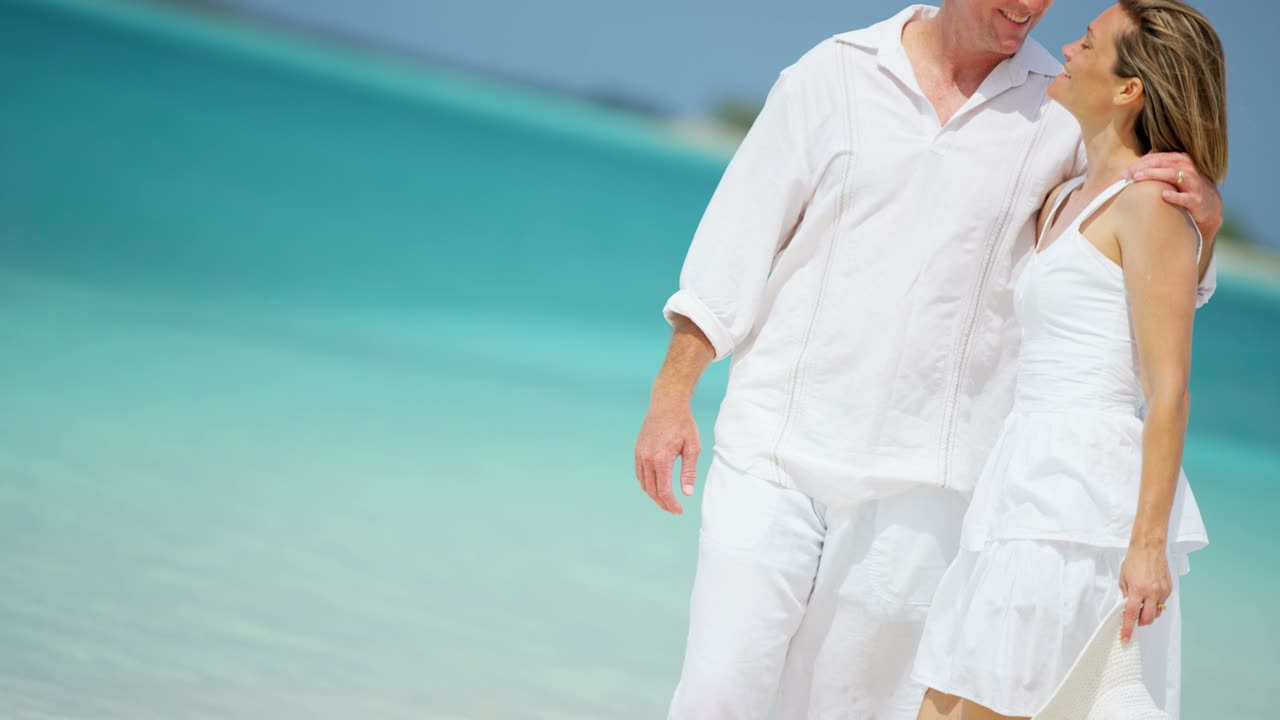 백인 부부가 열대 휴가 해변에서 함께 고 있습니다.