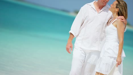 una pareja caucásica caminando juntos en una playa tropical de vacaciones.