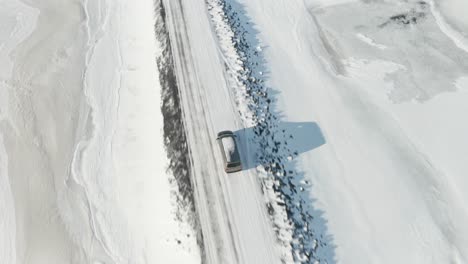 a tracking shot for a gray car traveling in the middle of the snow