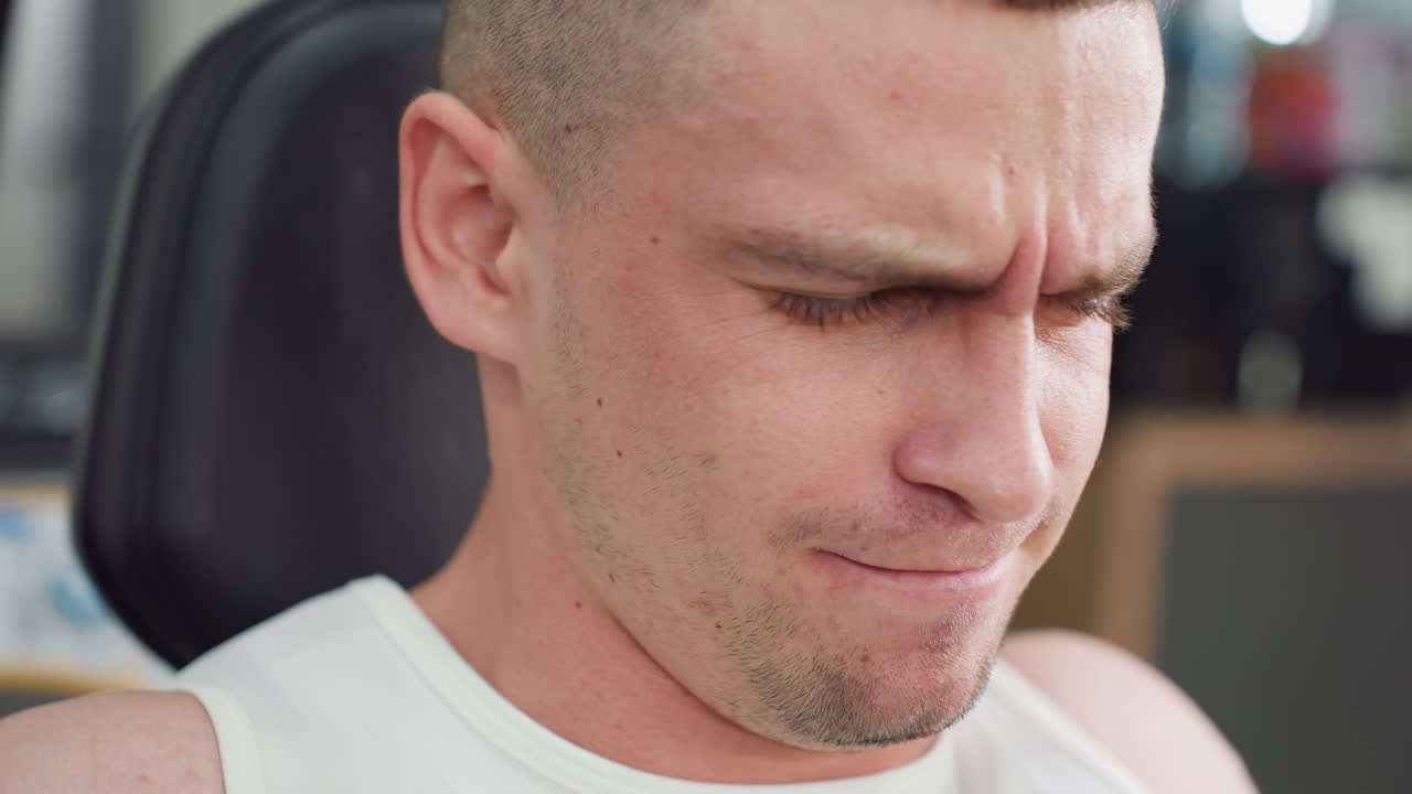 Close up of athlete face contorted in effort as he grips and pulls chest press handles up and down, muscles straining, veins visible and sweat dripping, intense workout focus in gym