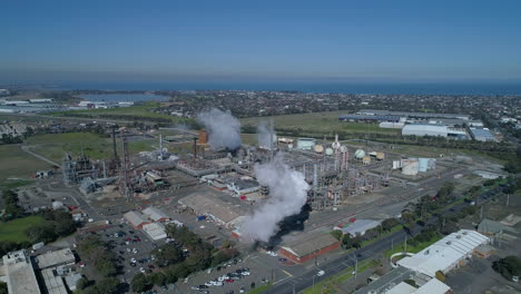 aerial shot of smoke stacks at industrial plant billowing smoke in slow motion