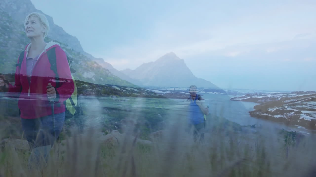 mature hikers climbing narrow mountain trail, showing animated health data and mountain chart