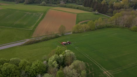 Hohe-Kreisförmige-Drohnenansicht-Eines-Traktors-Mit-Sprinkleranlage-Auf-Einer-Riesigen-Grünen-Wiese